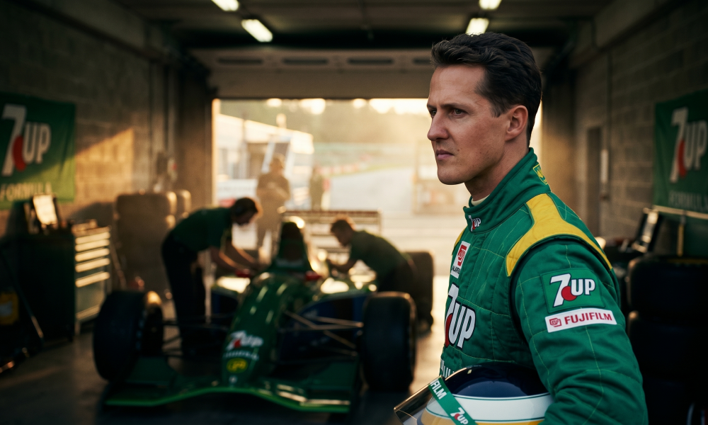 Young Michael Schumacher in Jordan F1 racing suit standing in garage next to Jordan 191 car at Spa-Francorchamps during his 1991 debut weekend