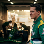 Young Michael Schumacher in Jordan F1 racing suit standing in garage next to Jordan 191 car at Spa-Francorchamps during his 1991 debut weekend