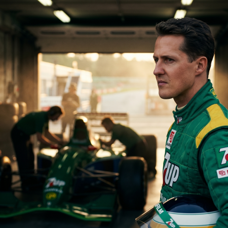 Young Michael Schumacher in Jordan F1 racing suit standing in garage next to Jordan 191 car at Spa-Francorchamps during his 1991 debut weekend