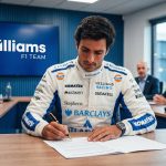 A detailed photograph capturing F1 driver Carlos Sainz, wearing his full Williams F1 Team race suit featuring logos for Barclays, Gulf, Komatsu, and Atlassian, seated at a wooden conference table and focused on signing a contract document with a pen. Behind him is a large screen displaying the Williams F1 TEAM logo, and several other team executives in formal attire are seated around the table.