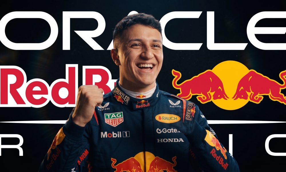 A smiling Red Bull Racing driver in a racing suit with sponsor logos, raising a fist in celebration, against a background that includes text for Oracle, Red Bull, and the team logos.