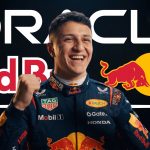 A smiling Red Bull Racing driver in a racing suit with sponsor logos, raising a fist in celebration, against a background that includes text for Oracle, Red Bull, and the team logos.
