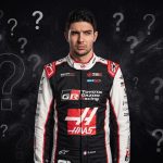 A serious-faced race car driver named E. Ocon, in his official Toyota Gazoo Racing and HAAS suit, stands against a dark background with numerous floating question marks.