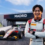 "A portrait of smiling Japanese F3 driver J. Nakamura at the IFEMA Madrid street circuit, standing near his #12 race car with clear visible 'MADRID' and 'IFEMA MADRID' branding."