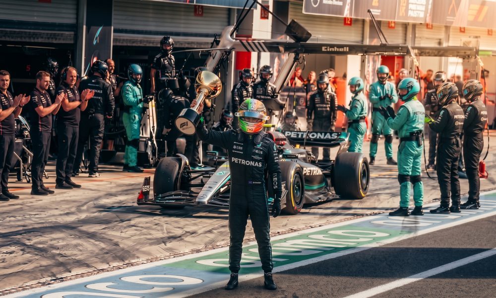 Formula 1 driver raising a trophy in the pit lane with the Mercedes AMG team.