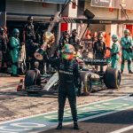 Formula 1 driver raising a trophy in the pit lane with the Mercedes AMG team.