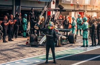 Formula 1 driver raising a trophy in the pit lane with the Mercedes AMG team.