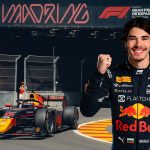 "Portrait of smiling Bulgarian F2 driver Nikola Tsolov in his Red Bull suit, fist raised, standing near his #12 F2 car at the IFEMA Madrid street circuit."