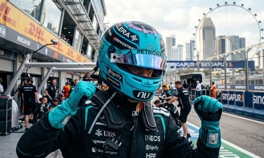 Mercedes Formula 1 driver celebrating in the pit lane at the Marina Bay Street Circuit in Singapore during the daytime.