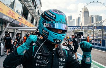 Mercedes Formula 1 driver celebrating in the pit lane at the Marina Bay Street Circuit in Singapore during the daytime.