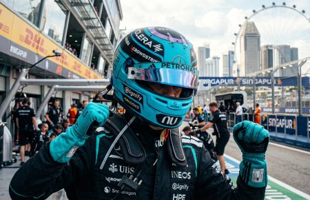 Mercedes Formula 1 driver celebrating in the pit lane at the Marina Bay Street Circuit in Singapore during the daytime.