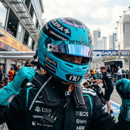 Mercedes Formula 1 driver celebrating in the pit lane at the Marina Bay Street Circuit in Singapore during the daytime.
